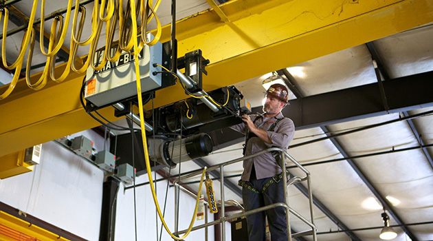 Technician performing preventive maintenance on a crane